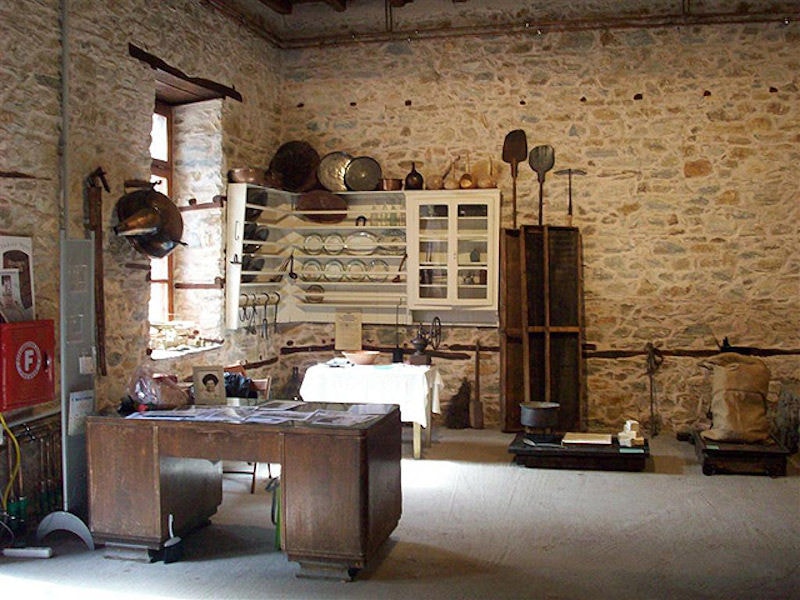cabinet and old ustensils on shelves at 'Olive and Olive Oil Museum, Sparta' on stone walls