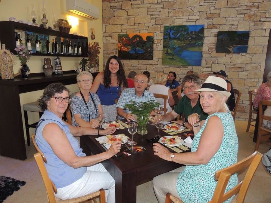 tourists smiling happily at the camera, eating and tasting wine at Olympia Land Estate winery