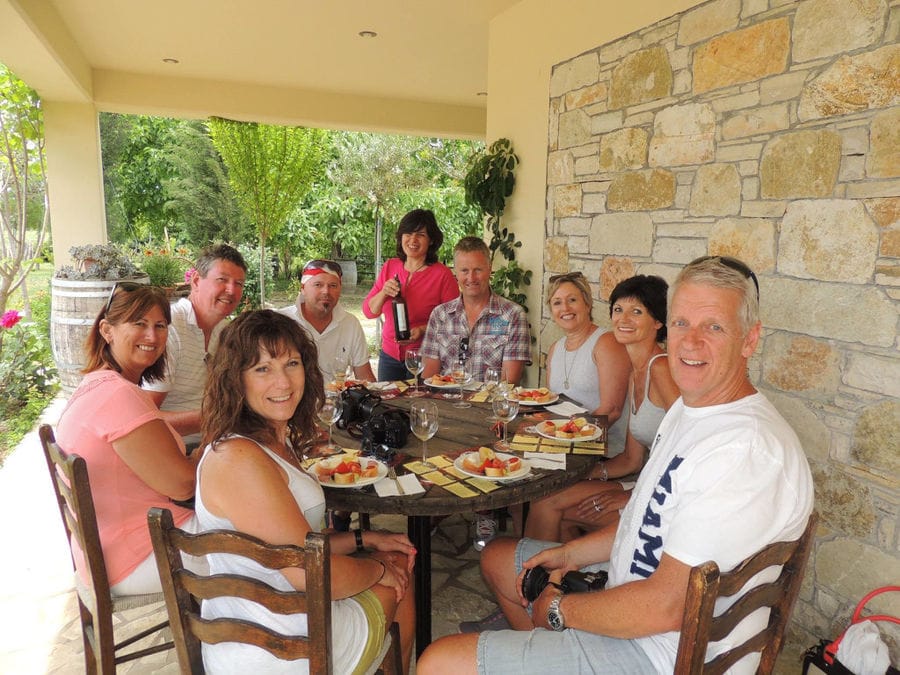 tourists smiling happily at the camera, eating and tasting wine at Olympia Land Estate winery