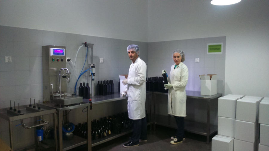 a couple at 'Pamako' olive oil plant laboratory and watching at the camera