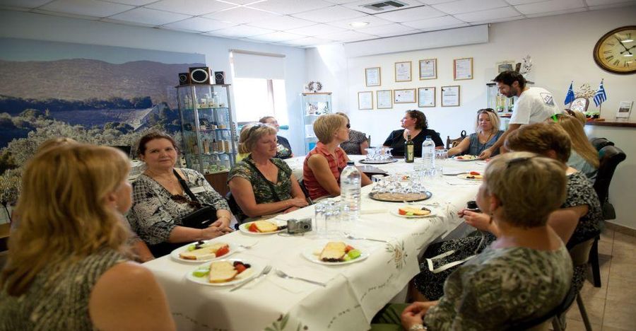 a group of tourists sitting at the tables in Melas Epidauros olive oil plant and eating