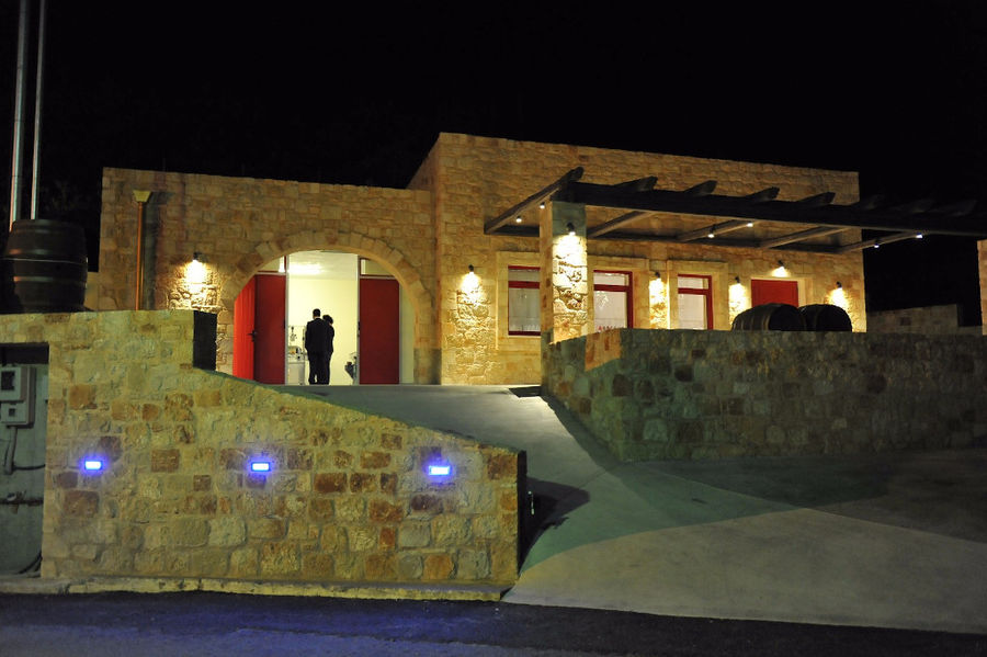 entrance of 'Piperis Winery' stone building with pavement by night