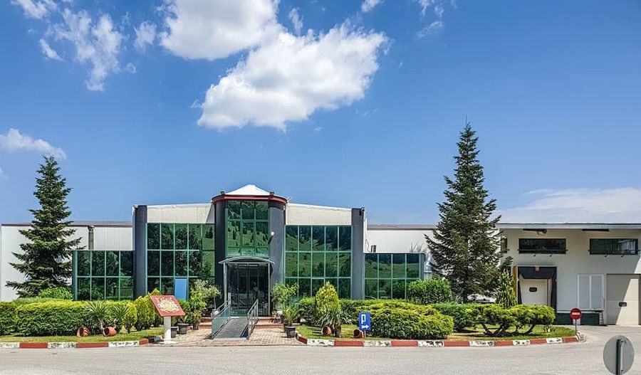 far view of front 'Pitenis' building with green plant bushes on the both sides of the entrance