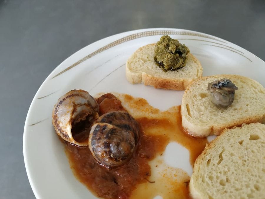 close-up of plate with marinated land snails and pieces of bread with paste snails from Feréikos