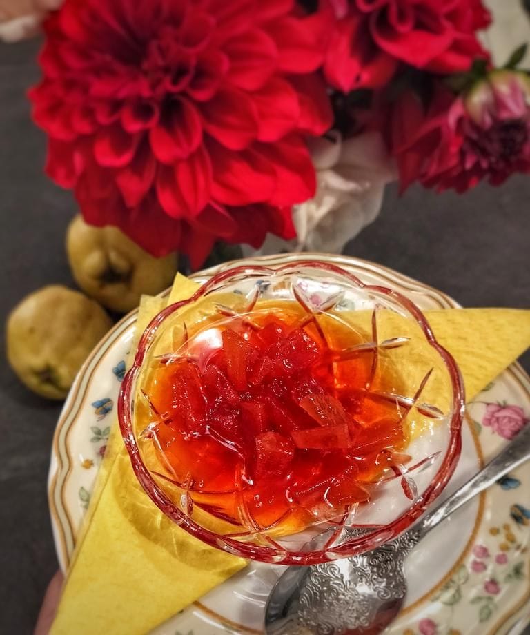 view from above of small bowl with red sweet spoon and flowers in the background at En Kefallinia Organic Farm Restaurant