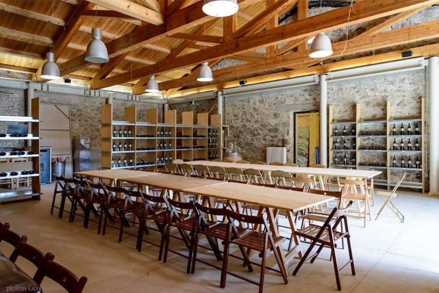 Pyrgos Vasilissis winery wine tasting room with wood tables and chairs