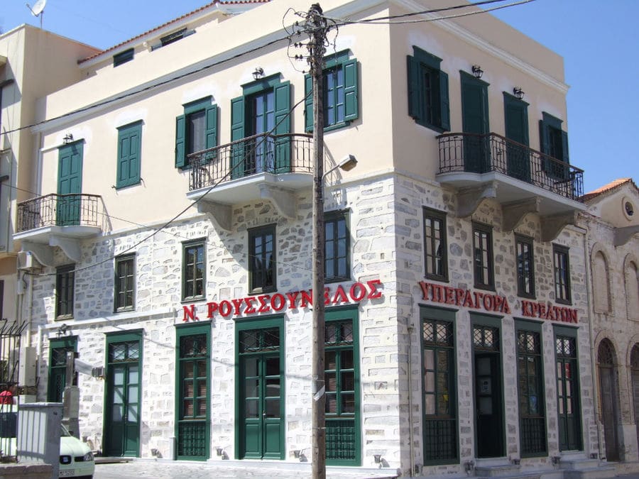 corner of the stone building with green shutters of 'Roussounelos Meat Market'