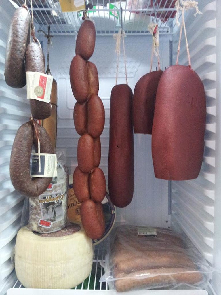 processed meat and sausages hanging in a fridge at 'Sary' and cheese on the shelve