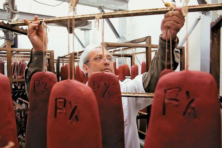 close-up of a man with white robe hanging processed meat at 'Sary'