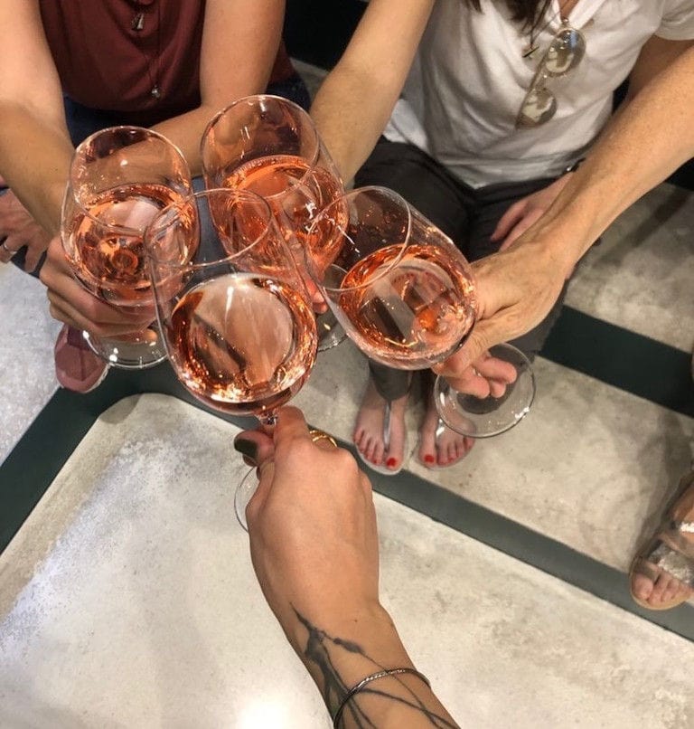 four tourists clink glasses with rose wine for 'cheers' 'Semeli Estate' winery