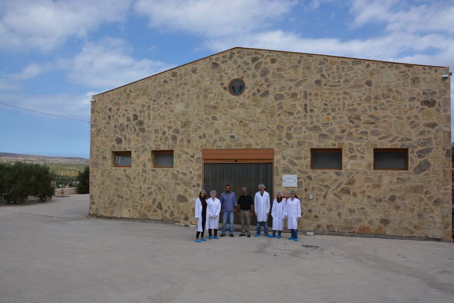 far view of a group of workers front the 'Si-Mel Honey Toplou' stone building