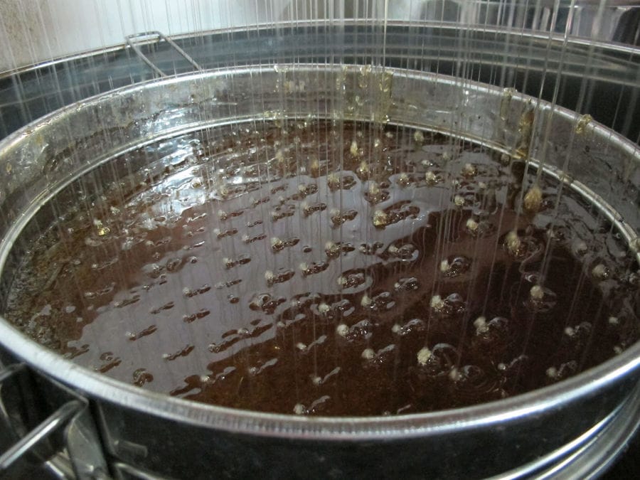 close-up of honey flowing in aluminum bucket at 'Si-Mel Honey Toplou' plant