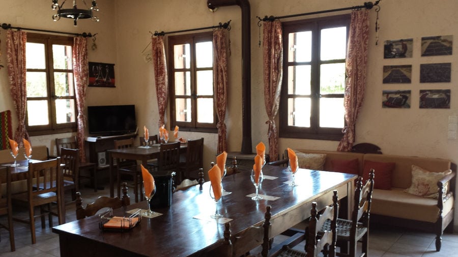 'Stilianou Winery' tasting room with wood tables and chaires and curtains at the windows