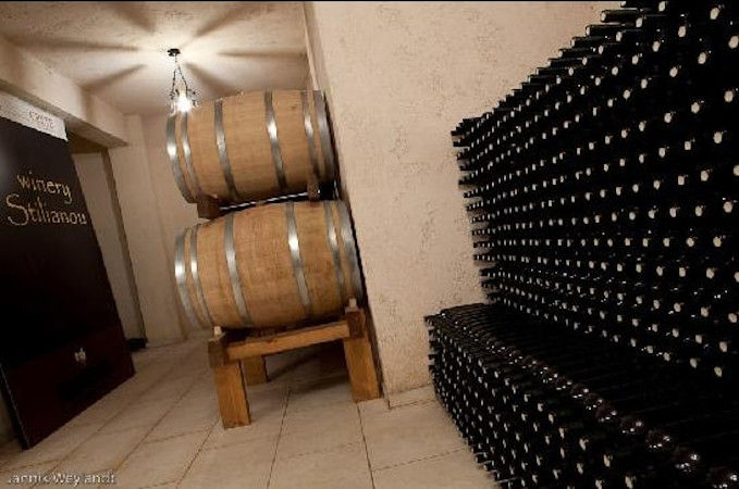 wine barrels and stacked bottles storaged in the wall at 'Stilianou Winery' cellar
