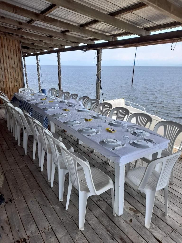 table with plastic chairs at the seaside restaurant set with plates and cutlery for visitors from Stefanos Kaneletis