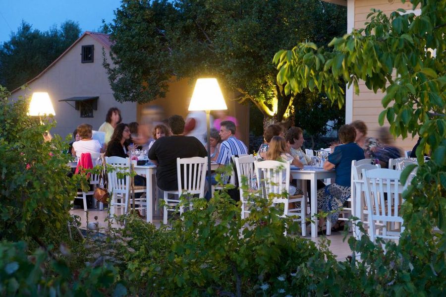 view of tables with tourists eating at En Kefallinia Organic Farm restaurant by night outside in the garden