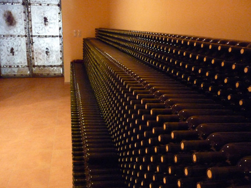 wine bottles on top of each other storaged on the ground in 'Theodorakakos Estate' cellar
