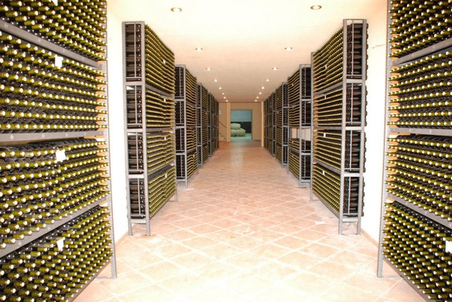 wine bottles on top of each other storaged on metalic frames in 'Theodorakakos Estate' cellar