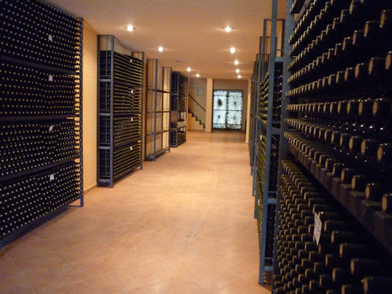 wine bottles on top of each other storaged on metalic frames in 'Theodorakakos Estate' cellar