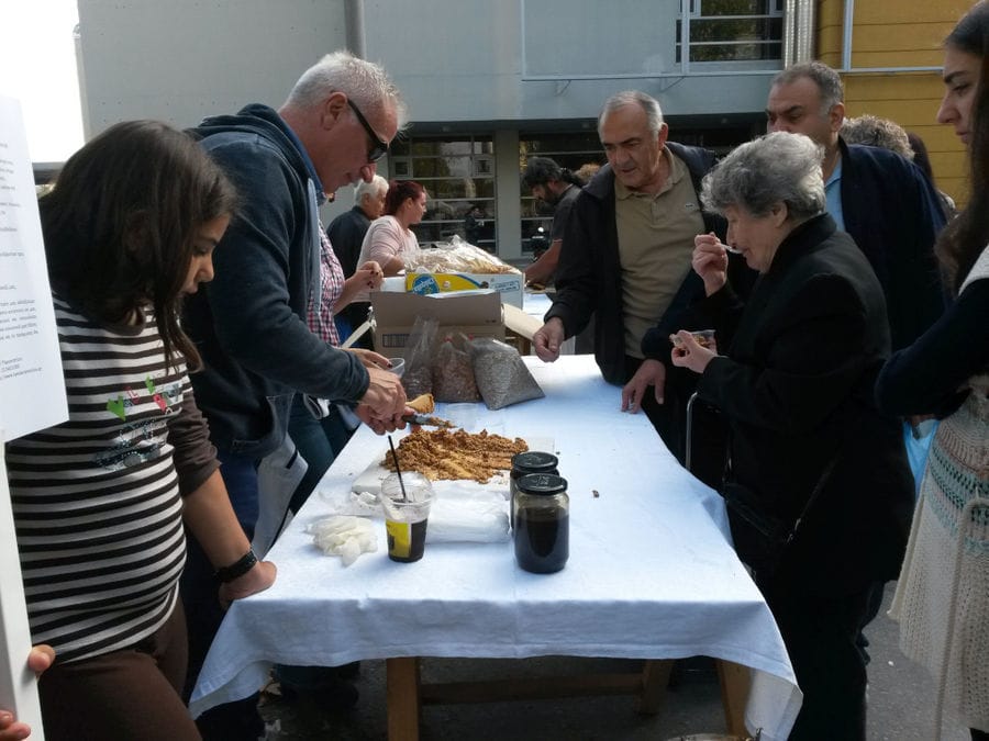 a group of tourists watching a man making honey-based superfoods at 'The Bear's Honey' and they tasting them