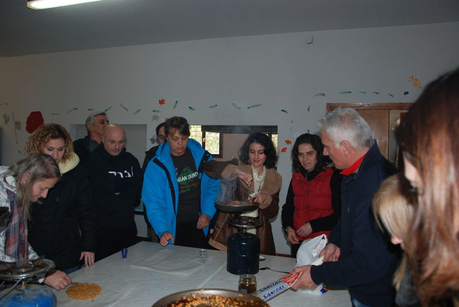 a group of tourists watching a man making honey-based superfoods on a camping gas in a pan at 'The Bear's Honey'