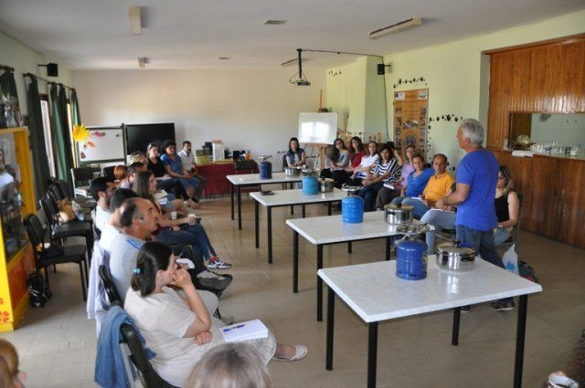 a group of tourists sitting and listening to a man that giving indications to make honey-based superfoods on camping gase at 'The Bear’s Honey'