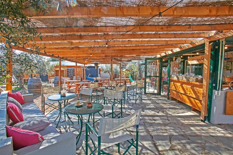 round tables and sofas at 'The Orchard in Vari' terrace covered with wooden beams