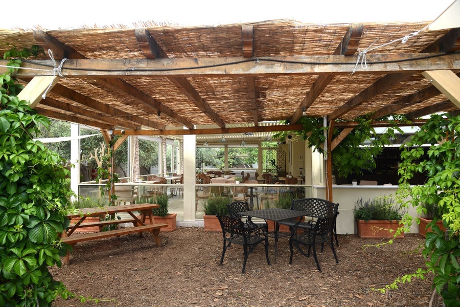 tables and benches at 'The Orchard in Vari' terrace covered with wooden beams