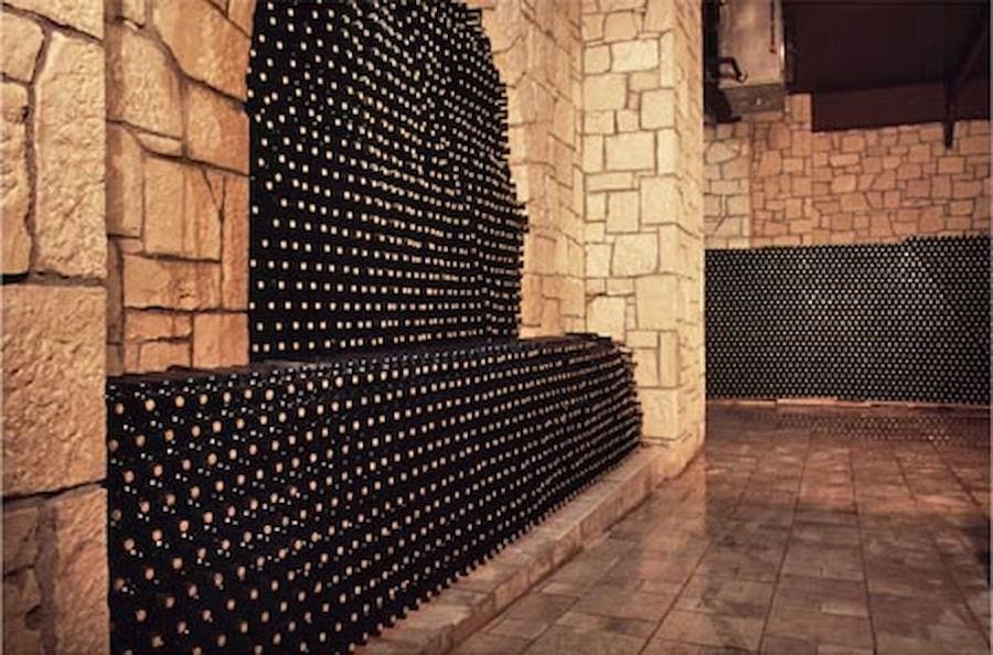 the stone wall of the cellar of Domaine Paterianakis with wine bottles storage on top of each other