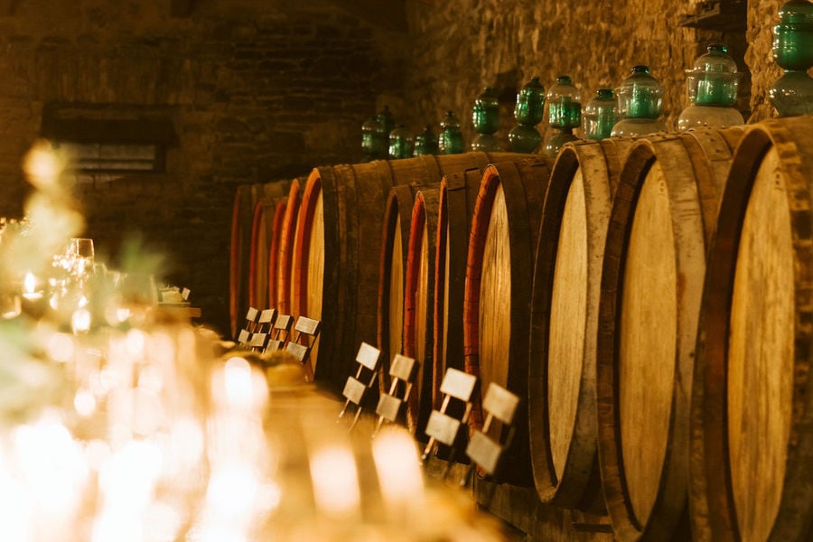 lying wine wood barrels in a row with gas lamps on the top of each one at 'Theotoky Estate' cellar
