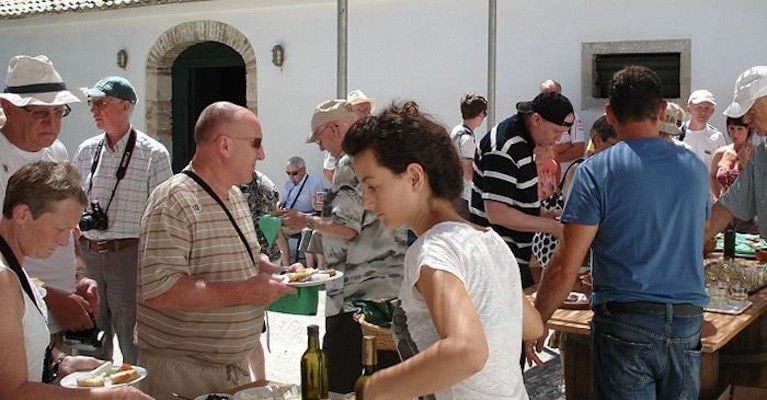 a group of tourists drinking and eating aperitifs at 'Theotoky Estate' outside