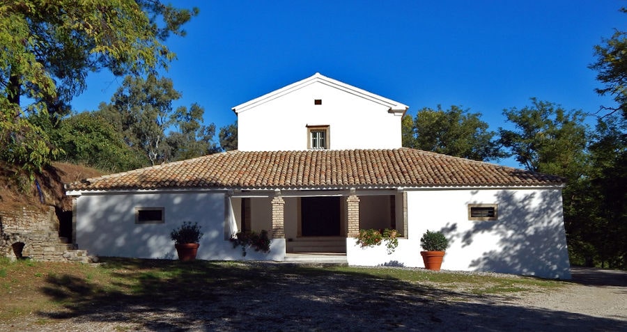 front view of 'Theotoky Estate' building with two columns surrounded by trees