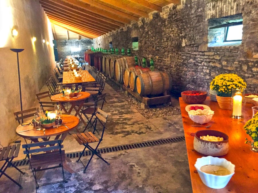 tables with glasses of wine and lying wine barrels on the one side at 'Theotoky Estate' stone cellar