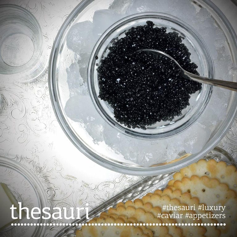 close-up of a bowl with caviar eggs from 'Thesauri Caviar' from above and a spoon in them