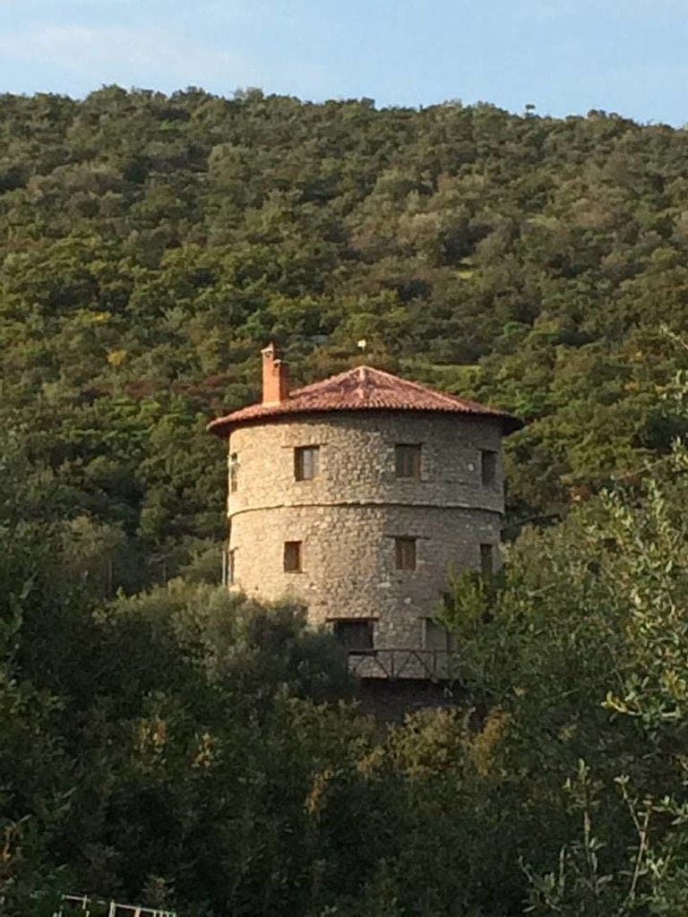 the stone tower of 'La Tour Melas' winery surrounded by trees