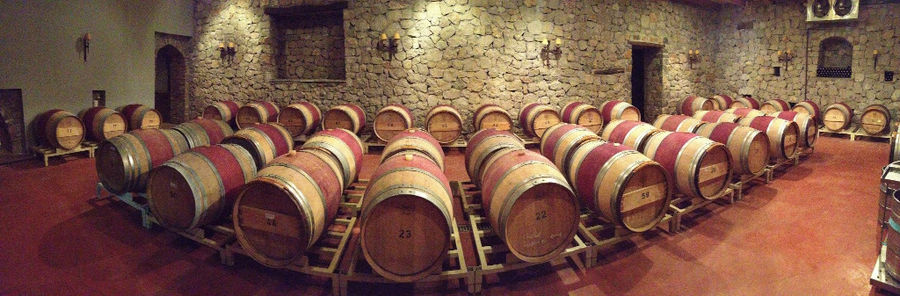 lying wine barrels in a row on the wood panels at 'La Tour Melas' corner stone cellar