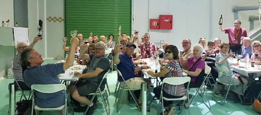 tourists sitting at the tables and raise their glasses with olive oil for cheers at Melas Epidauros plant