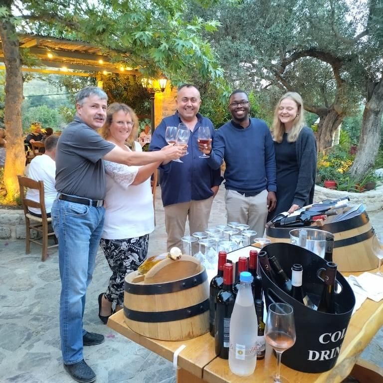 tourists clink glasses for 'cheers' and smiling at the camera at Ktima Toplou