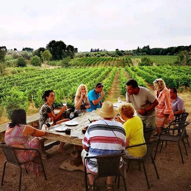 tourists sitting at the table and tasting wines outside at Domaine Dereskos vineyards