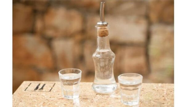 Close-up of bottle and glasses with Greek ‘raki’ is produced by distilling the grape