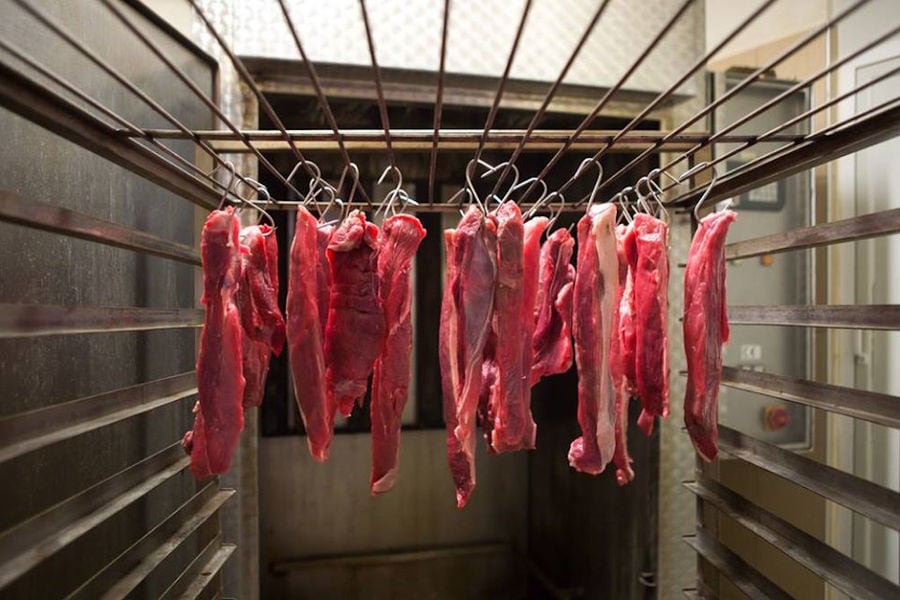 close-up of pieces of fresh meat hanging from metal hooks at Vavourakis Farm workshop