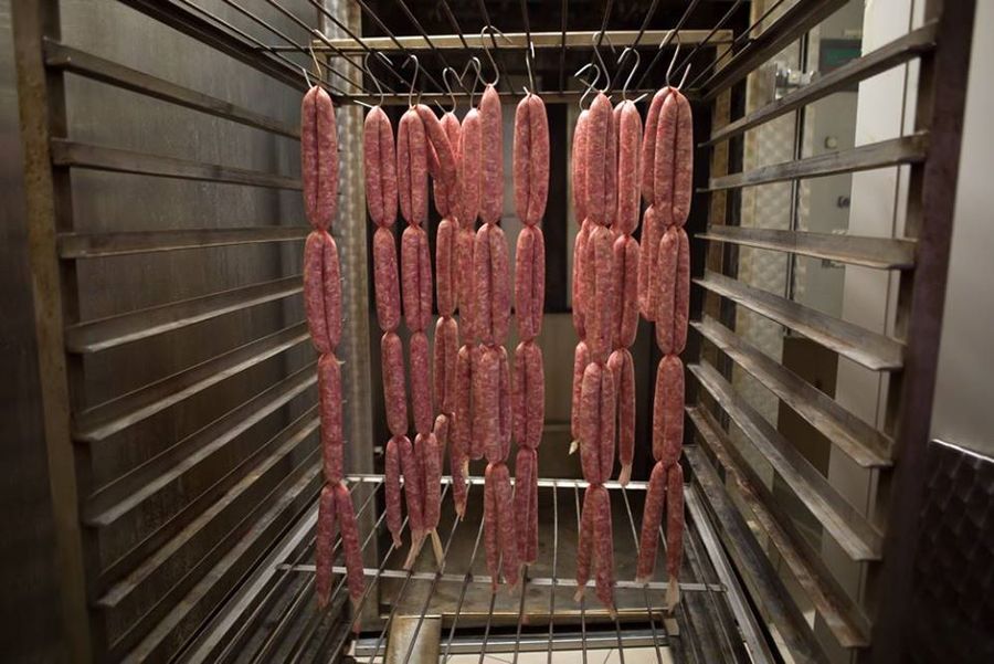 close-up of fresh sausages hanging from metal hooks to be dry at Vavourakis Farm workshop