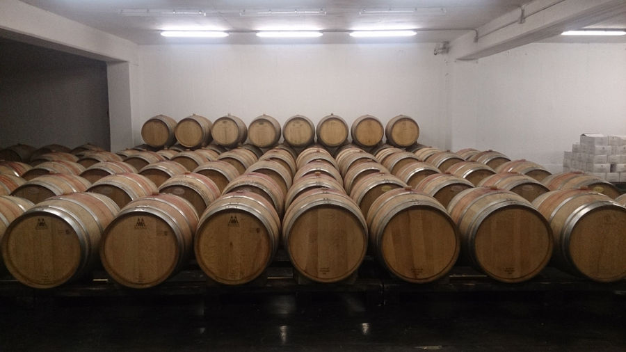 lying wooden barrels in a row on the metal frames at 'Voyatzis Estate' cellar