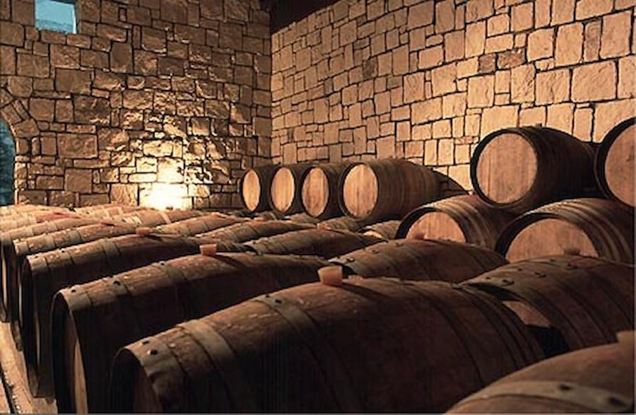 wine wooden barrels in Domaine Paterianakis stone cellar and someone are storage on top of each other