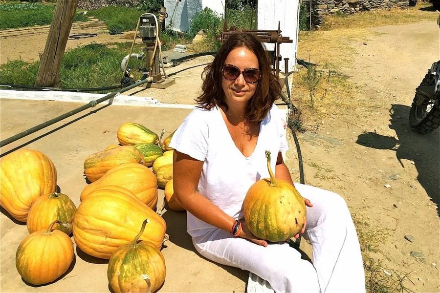 woman with glasses smiles at the camera and holds a gourd from Greek Cooking Class from Two Minutes Angie