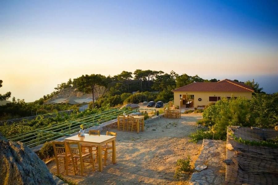 wooden tables with chairs outside at Afianes wines on stone pavement next to the vineyards