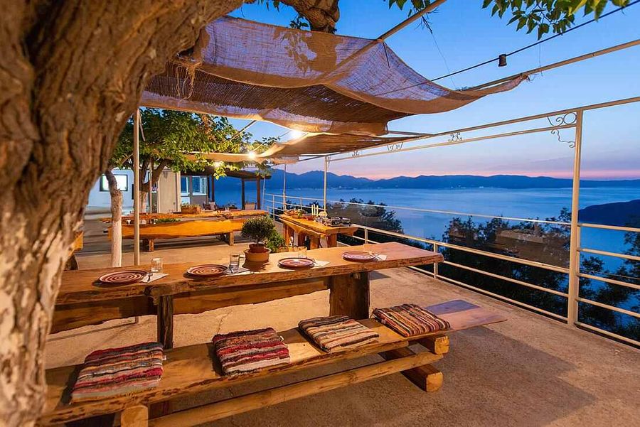 Dining area with tables and chairs by the sea, offering a serene view of the water.