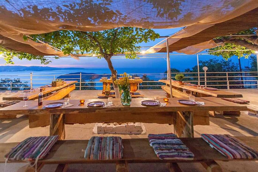 Dining area with tables and chairs by the sea, offering a serene view of the water.