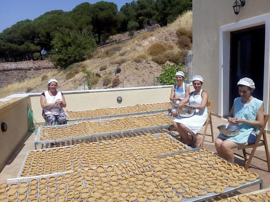 women watching at the camera and making 'kuluri' Greek pretzels and laying them to dry at the sun