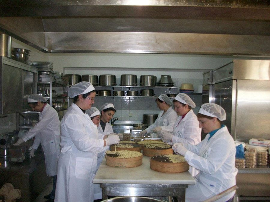 women on the both sides of table and making cakes at 'Agrotouristic Women's Cooperative of Mesotopos Lesvos' workshop